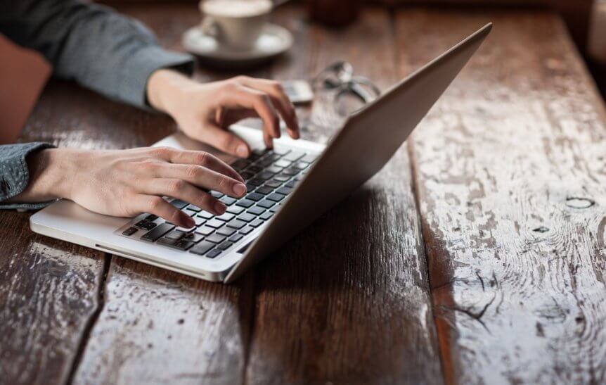 Man working on a laptop on a wood table.